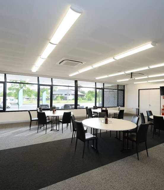 Swan Room with round tables, black chairs, and lake views through large windows